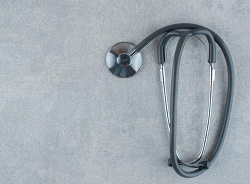 Black medical stethoscope on gray background