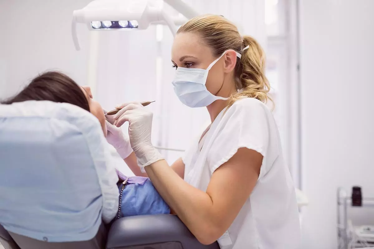 Dentist examining female patient in clinic